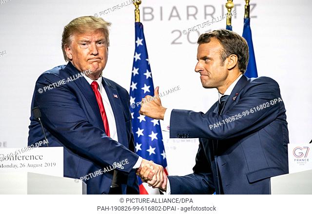 26 August 2019, France (France), Biarritz: Emanuel Macron (r), President of France, reaches out his thumb and shake hands with Donald Trump (l)