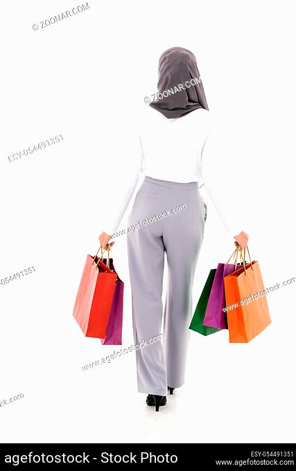Back view of Confident happy smiling female muslim woman with shopping bag. Studio shot on white background. Using for sale consumerism and shopaholic concept