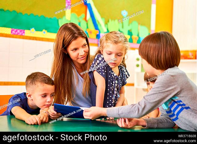 Kindergärtnerin oder Tagesmutter beim Buch vorlesen für Kinder im Hort oder im Kindergarten