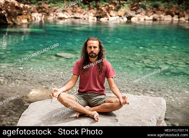 Man with long hair doing yoga on rock in front of Tara river