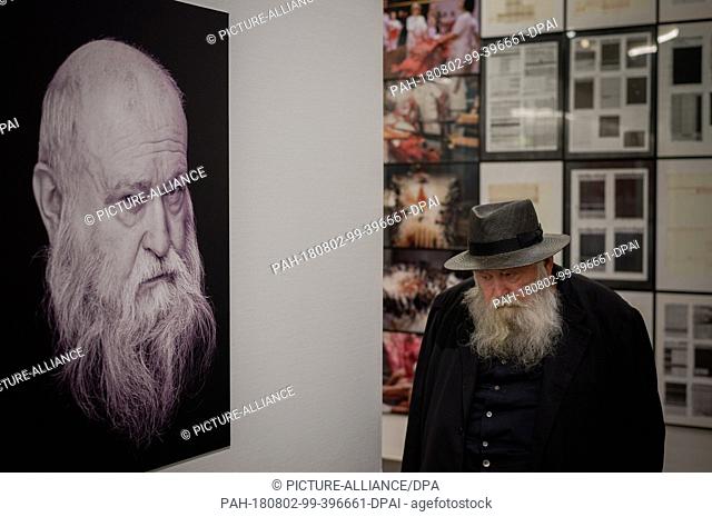 01 August 2018, Austria, Mistelbach: The Austrian painter and action artist Hermann Nitsch passes by a large portrait in the ""nitsch museum""