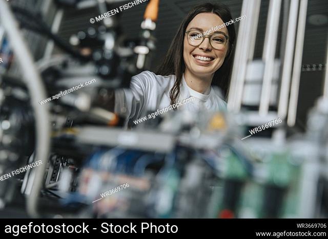 Close-up of smiling female scientist examining machinery in laboratory at factory