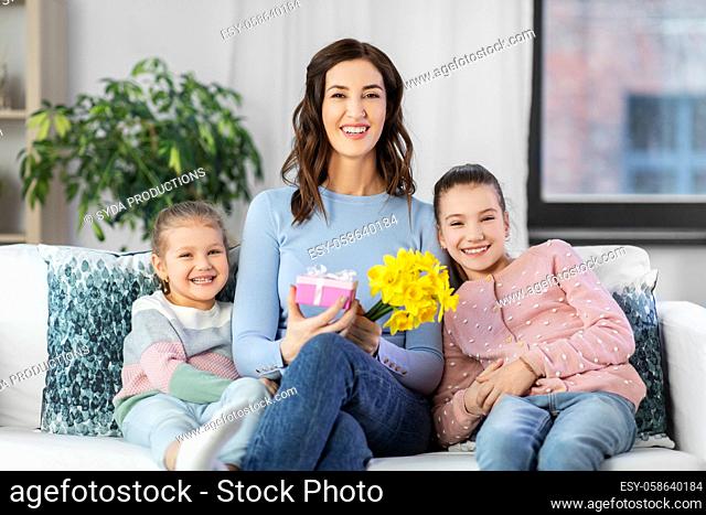 daughters giving flowers and gift to happy mother
