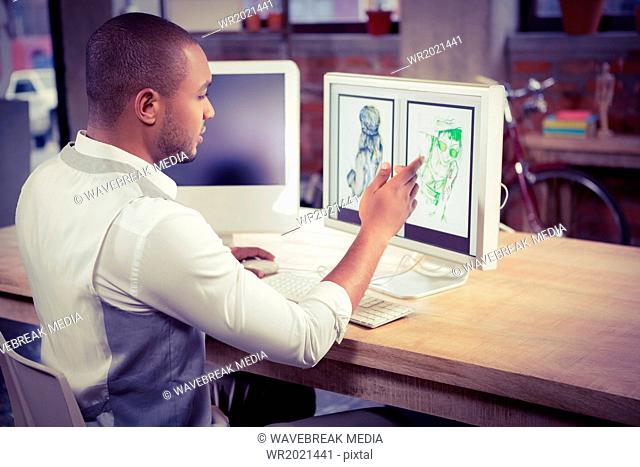 Cartoonist pointing at design on computer