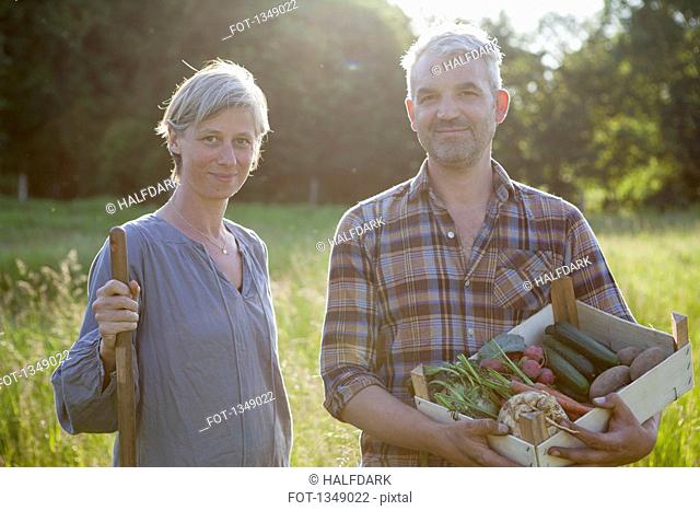 Portrait of mature couple with crate of freshly harvested vegetables at garden