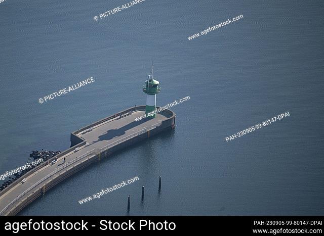 05 September 2023, Schleswig-Holstein, Lübeck: A person rides a bicycle to the pier light Travemünde (aerial view from helicopter)