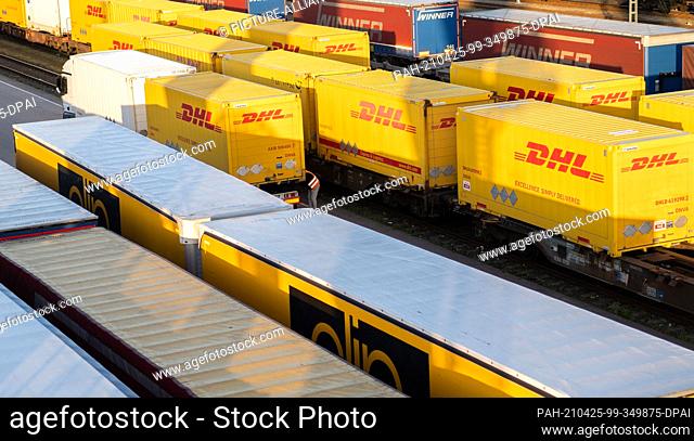 25 April 2021, North Rhine-Westphalia, Wuppertal: A truck driver stands by his truck between DHL containers at the freight terminal in Langerfeld