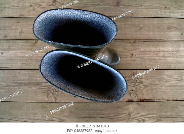 Rubber boots on the wooden floor. Abstract background image. View from above. Top view of farmer rubber boots standing on wooden floor