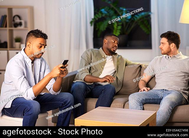 man using smartphone while friends talking at home