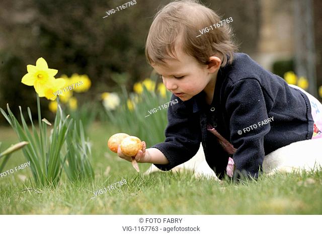 GERMANY, GAGGENAU, 03.04.2009, Little Child is sitting in a flowerfield with Easter Egs - Gaggenau, Baden-Württemb, GERMANY, 03/04/2009