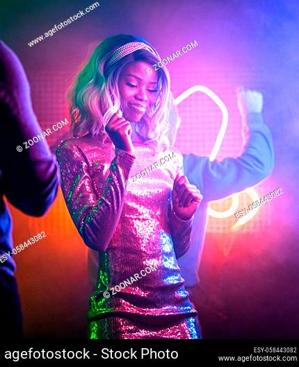 Happy African girl dancing in night club. Pretty African American woman having fun bright neon glowing. Night life concept. Entertainment concept
