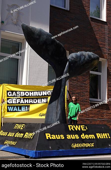 12 July 2022, North Rhine-Westphalia, Essen: Greenpeace activists protest with a homemade whale tail fin in front of the RWE headquarters in Essen