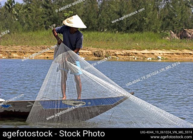 Conical hat man hand casting net fishing Thu Bon River in Hoi An historic town mid Vietnam
