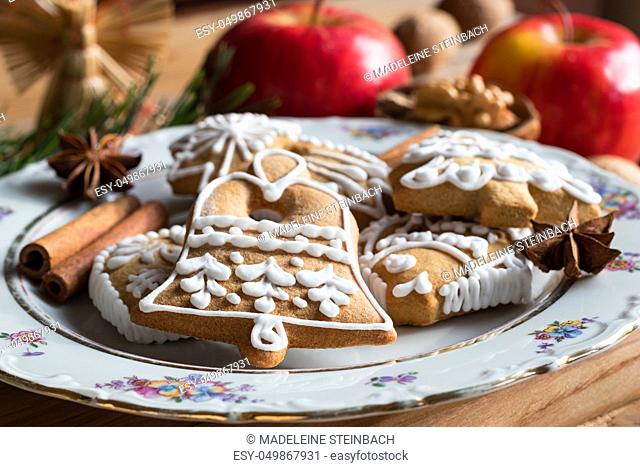 Christmas gingerbread cookies on a plate, with apples, spices and nuts in the background