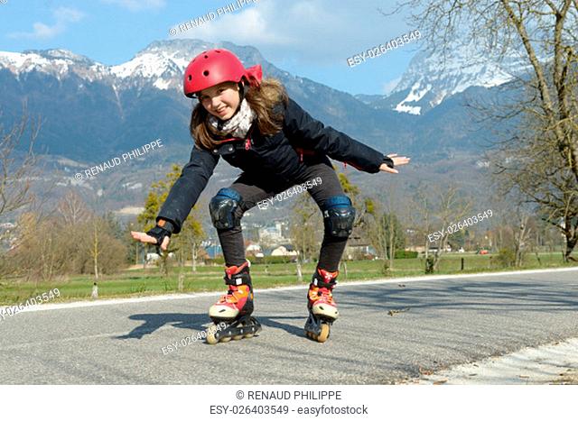 a pretty preteen girl on roller skates in helmet at a track