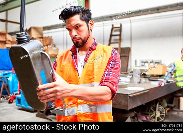 Lagerarbeiter an Bedienfeld einer Maschine oder einem Kran in der Metallbau Fabrik