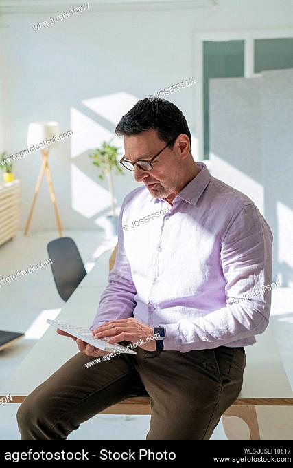 Mature businessman using computer keyboard sitting on table at office