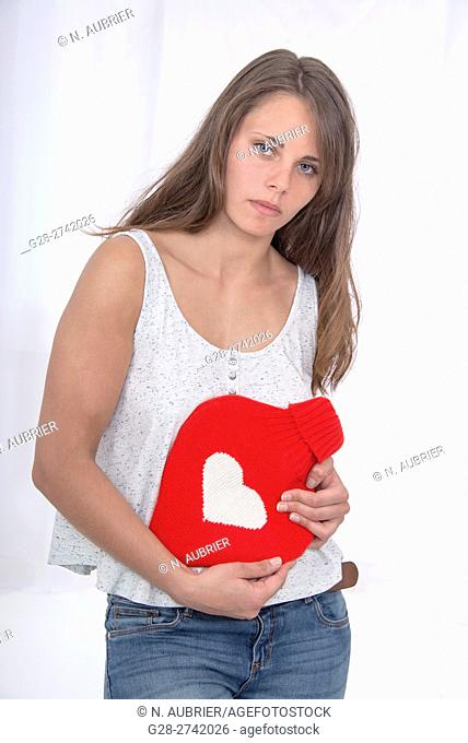 Young woman holding a heart-shaped hot water bottle on her stomach