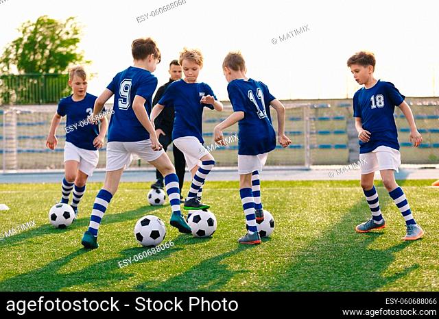 Group of children playing soccer on training session. Kids in football club wearing blue jersey shirts and soccer kits. Happy boys practicing football with...