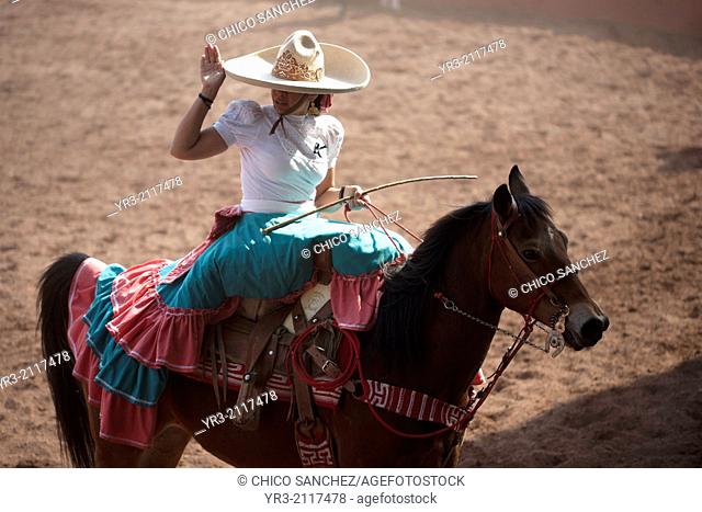 "An escaramuza salutes as she rides her horse before competing in an Escaramuza in the Lienzo Charros el Penon, Mexico City, Sunday, January 19, 2013