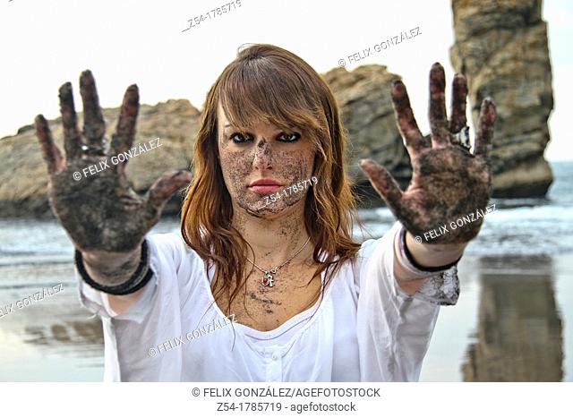 Attractive young Woman at El Sablón beach, with sand in her face and hands, Asturias, Spain