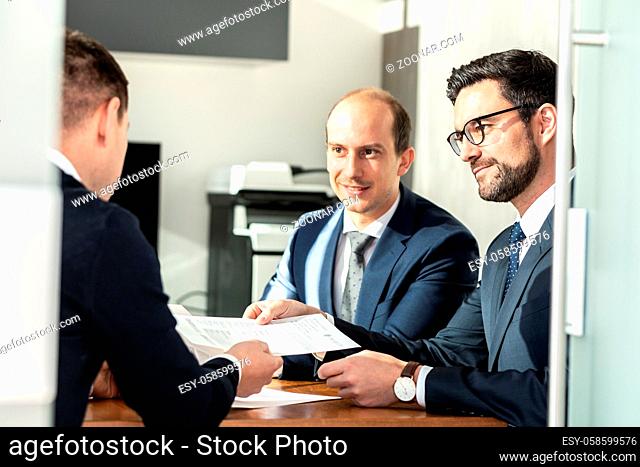 Team of confident successful business people reviewing and signing a contract to seal the deal at business meeting in modern corporate office