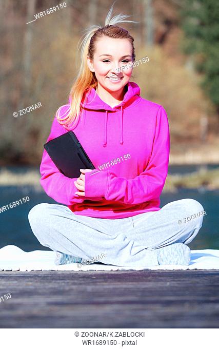 Woman teenage girl in tracksuit using tablet on pier outdoor