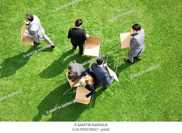 Business people carrying chairs outdoors