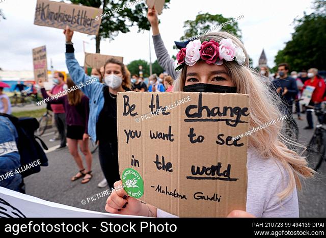 23 July 2021, Hamburg: Climate activist Luisa Neubauer (l) demonstrates next to a demonstrator with a sign reading ""Be the change you want to see in the...