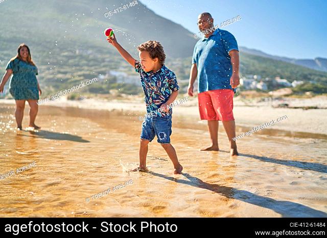 Cute boy playing with tennis ball in ocean surf