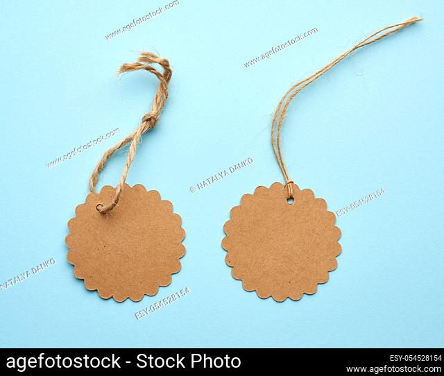 Round empty brown paper tag tied with string. Price, gift, sale tag on a blue background, close up