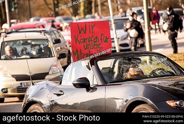20 February 2021, Hamburg: Participants of a motorcade against Corona measures drive through the city centre with a sign reading ""We fight for our employees""