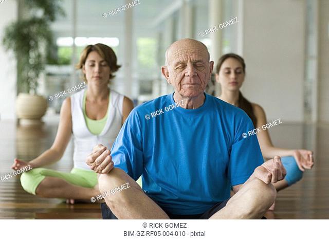 Senior man and two women meditating at health club