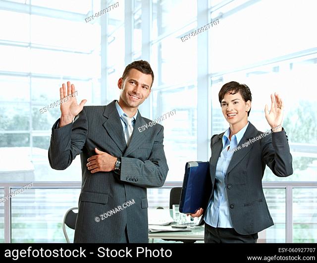 Businessman and businesswoman waving hands, greeting somebody before meeting