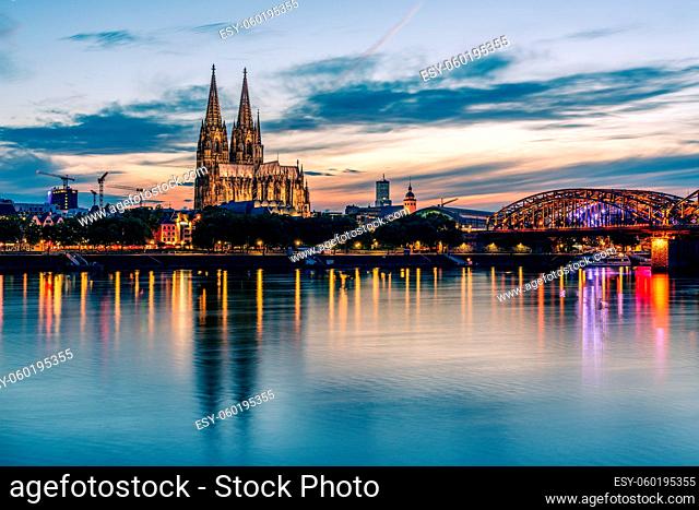 Panoramic view of Cologne Cathedral with Hohenzollern Bridge at nightfall, Germany
