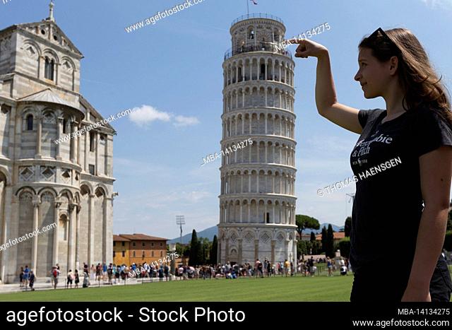 a typical tourist image of the leaning tower of pisa, toscany, italy, where the tourist looks as if he is supporting the tower