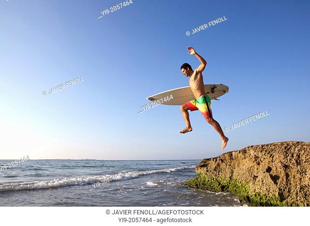 Man jumping into the water with his surf board