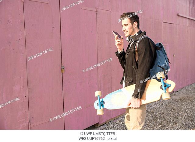 Young man with skatebaord and cell phone on the move