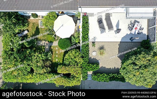 11 August 2020, Baden-Wuerttemberg, Ravensburg: A clearly structured rockery (r) with a massive tree and cherry laurel hedge borders a well-kept green garden...