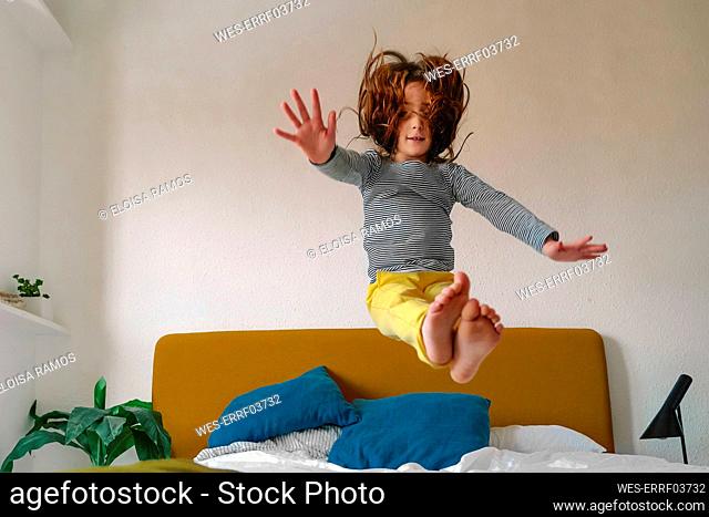 Girl jumping on bed at home