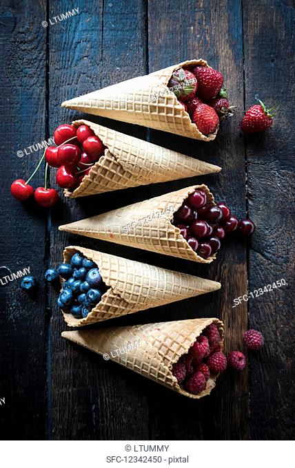 Various berries and cherries in ice cream cones