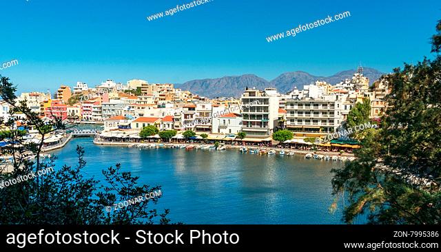 AGIOS NIKOLAOS, GREECE - JULY 20, 2014: Waterfront with outdoor greek tavern, small shops and boats in harbor of Agios Nikolaos, Crete, Greece