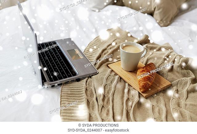 laptop, coffee and croissant on bed at cozy home