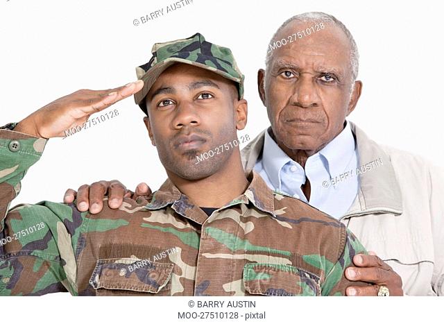 Portrait of US Marine Corps soldier with father saluting over gray background