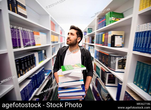 Student holding lot of books in school library. Hard worker and persistence concept