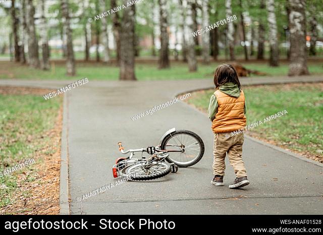Boy standing near fallen bicycle at park