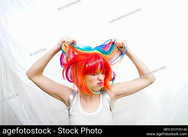 Woman pulling hair in front of plastic backdrop