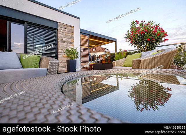 Lounge furniture on a modern terrace with reflection in glass table top