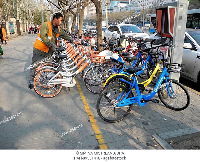 A man parks a bicycle of the rental bike company 'mobike' on a street in Beijing, China, 28 March 2017. Photo: Simina Mistreanu/dpa | usage worldwide