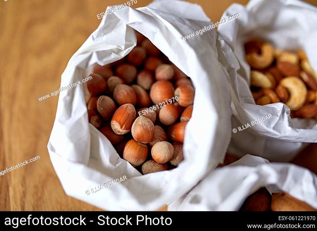 Top view Various sort of nuts on the table in a paper bag on wooden background, shopping grocery concept, nuts delivary, Zero Waste Food Shopping